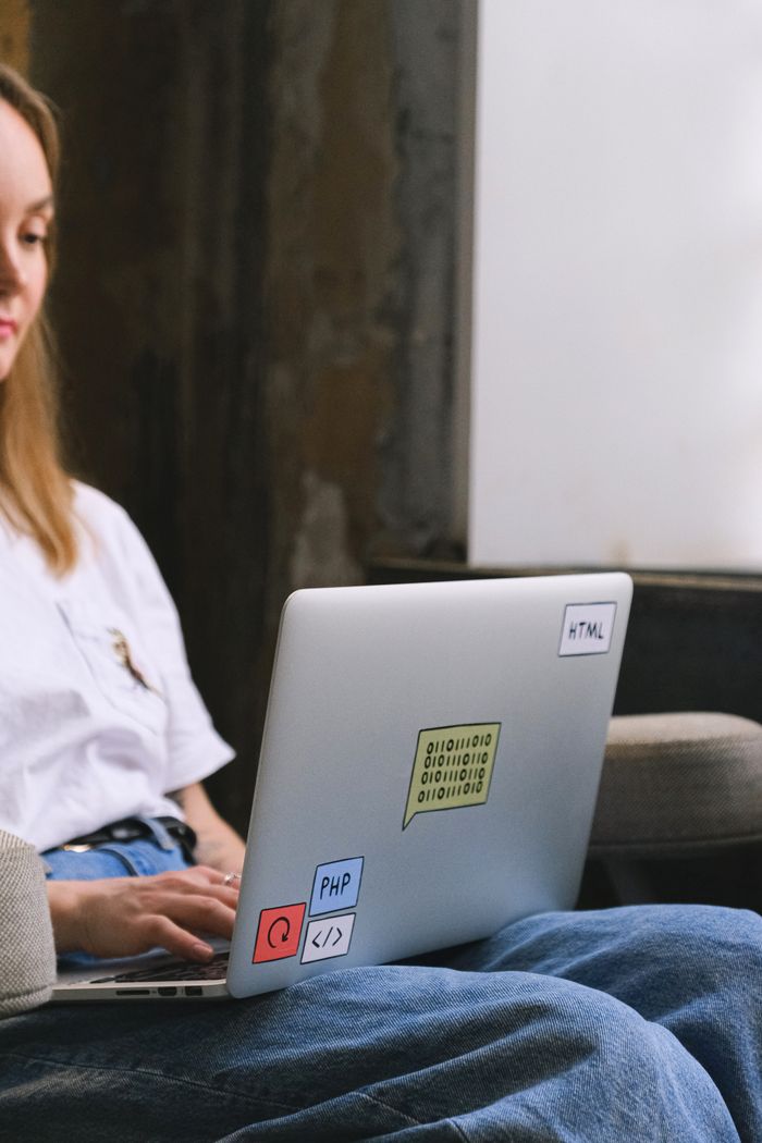 About A woman is remote working on her laptop, showcasing coding and technology-related stickers.
