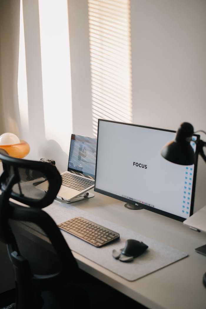 A minimalist home office setup featuring a monitor displaying 'FOCUS', promoting productivity with modern aesthetics.